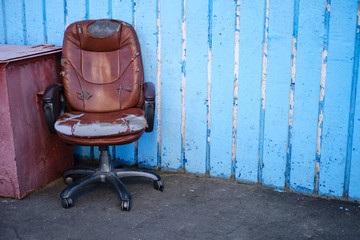 Shabby old leather executive chair, concept of financial problems. Blue wall with place for text, copy space