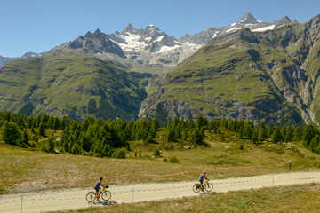 People riding bikes at Sunnegga over Zermatt in the Swiss alps - obrazy, fototapety, plakaty