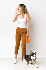 A full length young pretty woman with her dog shouting with mouth wide open to the lateral