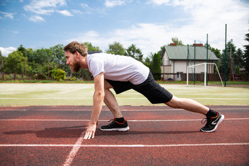 A starting position of a sprinter on a running track, side view.