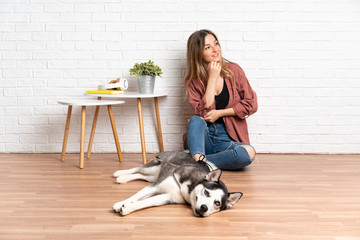 Young girl with her dog sitting in the floor at indoors looking side