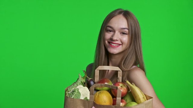 Smiling woman with groceries shopping bag full of healthy vegetables and fruits