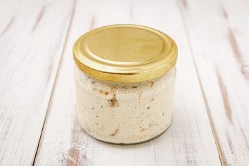 White product, paste in a glass jar on a light wooden background.