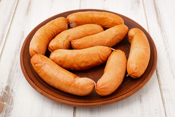 sausages on a plate on a white wooden background.