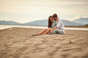 Fototapeta na wymiar Young couple in love sitting in a hug on the beach