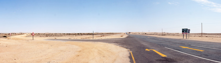 Unpaved road through the Namib desert in West Namibia; some roads signs fill the emptyness.