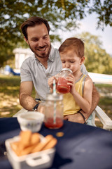 Father with  son sitting at table outdoor and  enjoying together.