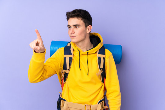 Teenager caucasian mountaineer man with a big backpack isolated on purple background touching on transparent screen - Powered by Adobe
