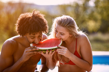 Man and girl enjoy on summer holiday near swimming pool and  eating watermelon.