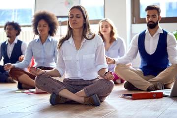 Young colleagues having yoga in the office; Mindfullnes in the office concept - 372921321
