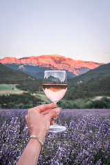 Verre de vin rosé au coucher de soleil avec la vue sur le champs de lavande et la montagne