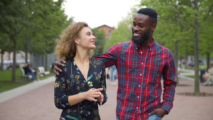 Beautiful diverse young couple in love walking in summer park