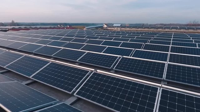 Rows of solar panels at sunlight. Photovoltaic solar cells on the modern electricity farm on flat roof. Renewable source of clean energy from the sun. Drone flight.