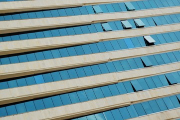 Fototapeta na wymiar Modern multistory building with blue shiny windows and white facade.
