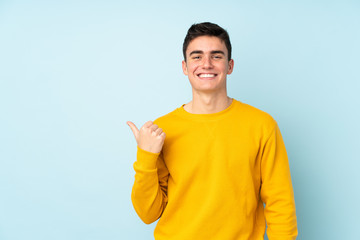 Teenager caucasian handsome man isolated on purple background pointing to the side to present a...