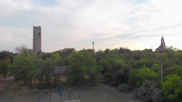 Industrial mining mine red iron ore headframe aerial drone takeoff up camera movement sunset Krivoy Rog Ukraine