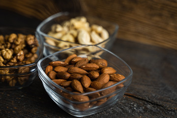 Almond, pistachio and walnut in a small plates which standing on a black table. Nuts is a healthy vegetarian protein and nutritious food.