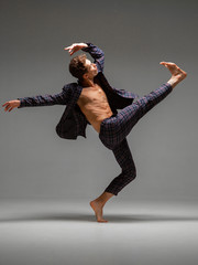 Cool young man dancer dancing expressive dance in suit in studio. Dance school poster. Dance lessons