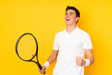 Handsome teenager tennis player man isolated on yellow background playing tennis and celebrating a...