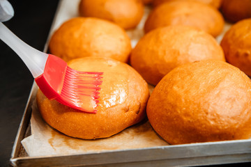 Smearing buns with egg yolk with kitchen brush