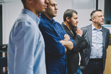 Cropped image of group of confident marketing experts standing together in office and discussing creative ideas for business project.Crew of professional employees communicating during collaboration