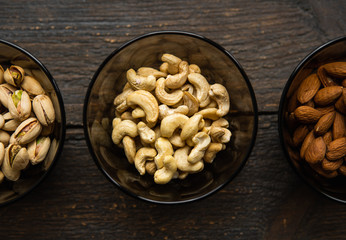 Almond, pistachio and cashew in a small plates which standing on a black table. Nuts is a healthy vegetarian protein and nutritious food.