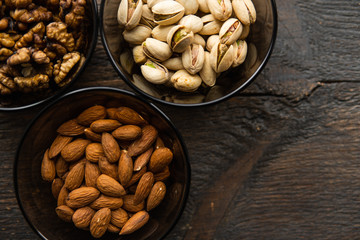 Almond, pistachio and walnut in a small plates which standing on a black table. Nuts is a healthy vegetarian protein and nutritious food.