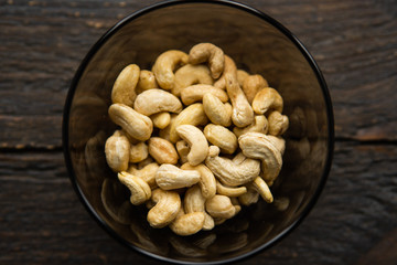 Cashew nuts in a small plate on a vintage wooden table as a background. Cashew nut is a healthy vegetarian protein nutritious food.