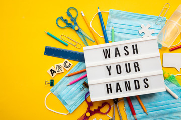 Wash your hands lightbox message with school equipment and covid masks
