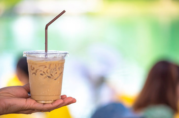 Glass of cold espresso coffee in hand Background blurry views.