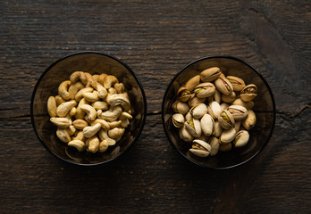 Walnut, pistachio and cashew in a small plates which standing on a black table. Nuts is a healthy vegetarian protein and nutritious food.