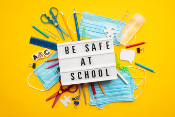 Be safe at school message with school equipment and covid masks