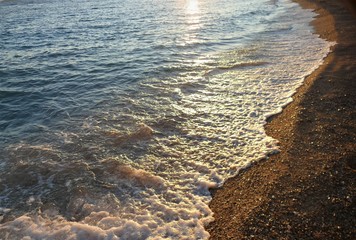 Beach with golden sea and waves in sunset