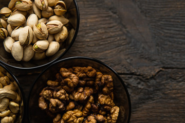 Walnut, pistachio and cashew in a small plates which standing on a black table. Nuts is a healthy vegetarian protein and nutritious food.