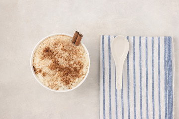 Delicious dessert rise pudding with cinnamon and raisin in bowl, top view, flat lay. Served and ready to eat.