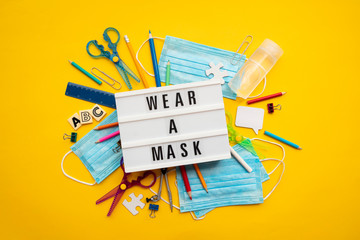 Wear a mask lightbox message with school equipment and covid masks