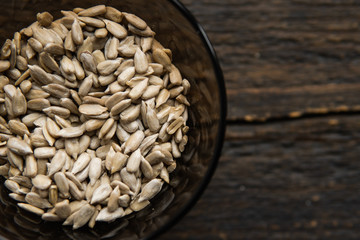 Sunflower seeds in a small plate on the wooden vintage table. Healthy vegetarian protein nutritious food. Sunflower seed on rustic old wood.