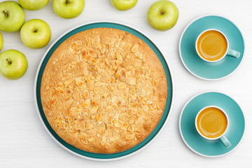 Homemade pastry. Apple pie with almond petals and two cup of coffee espresso on white wooden table. Top view.