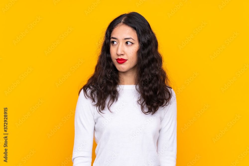 Sticker mixed race woman over isolated yellow background standing and looking to the side