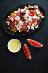 Grapefruit, feta cheese and cherry tomatoes salad, studio shot on a black stone background, top view