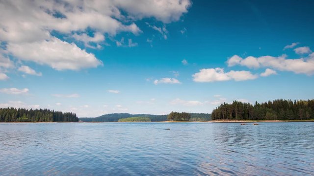 Timelapse with beautiful summer morning view of а mountain lake and moving white fluffy clouds at Shiroka Polyana Dam in the Rhodope Mountains, Bulgaria