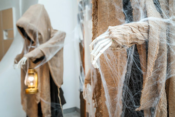 Halloween holiday. A figure with a cape with a skeleton hand holding a lantern. The figure is...