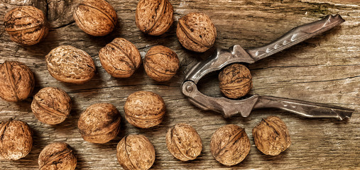 Vintage nutcracker and whole walnuts on a natural wooden background. View from above.