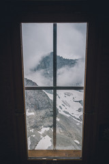 Fototapeta na wymiar Montagne brumeuse à travers de la fenêtre du refuge 