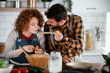 Boyfriend and girlfriend making delicious food at home. Loving couple cooking in kitchen..