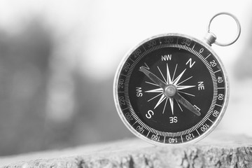 black and white photo of round compass as symbol of tourism, travel and outdoor activities