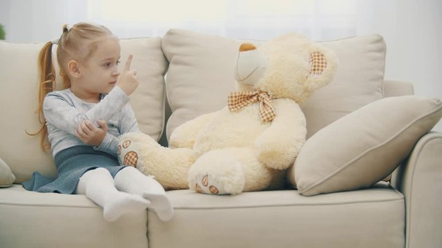 4k slowmotion video of little girl teaching her teddy bear.