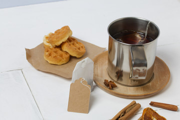 Mug of tea and waffles. Nearby are cinnamon, anise and dried oranges on the table. Autumn still life.