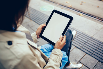 Cropped view of young woman's hands holding digital tablet device with mock up area on display for your website content.Hipster girl with modern touch pad with advertising area on blank screen