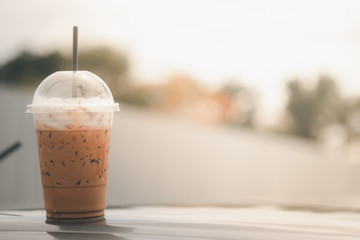 Ice coffee in plastic cup put on roof of car